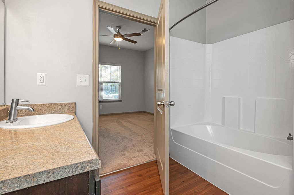 A bathroom with a sink, mirror, and bathtub.